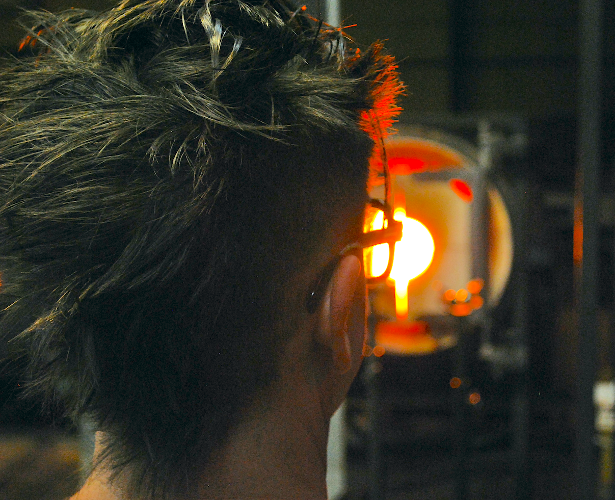 Picture of the back of someones head in a glass blowing studio